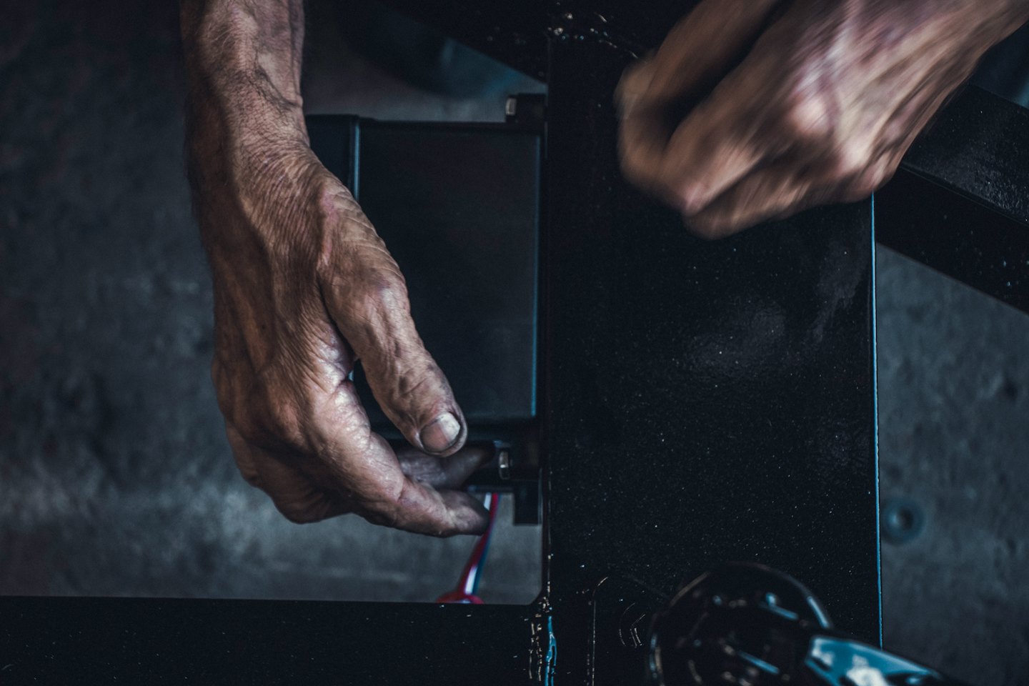 Hands connecting colorful wires to an electrical component.