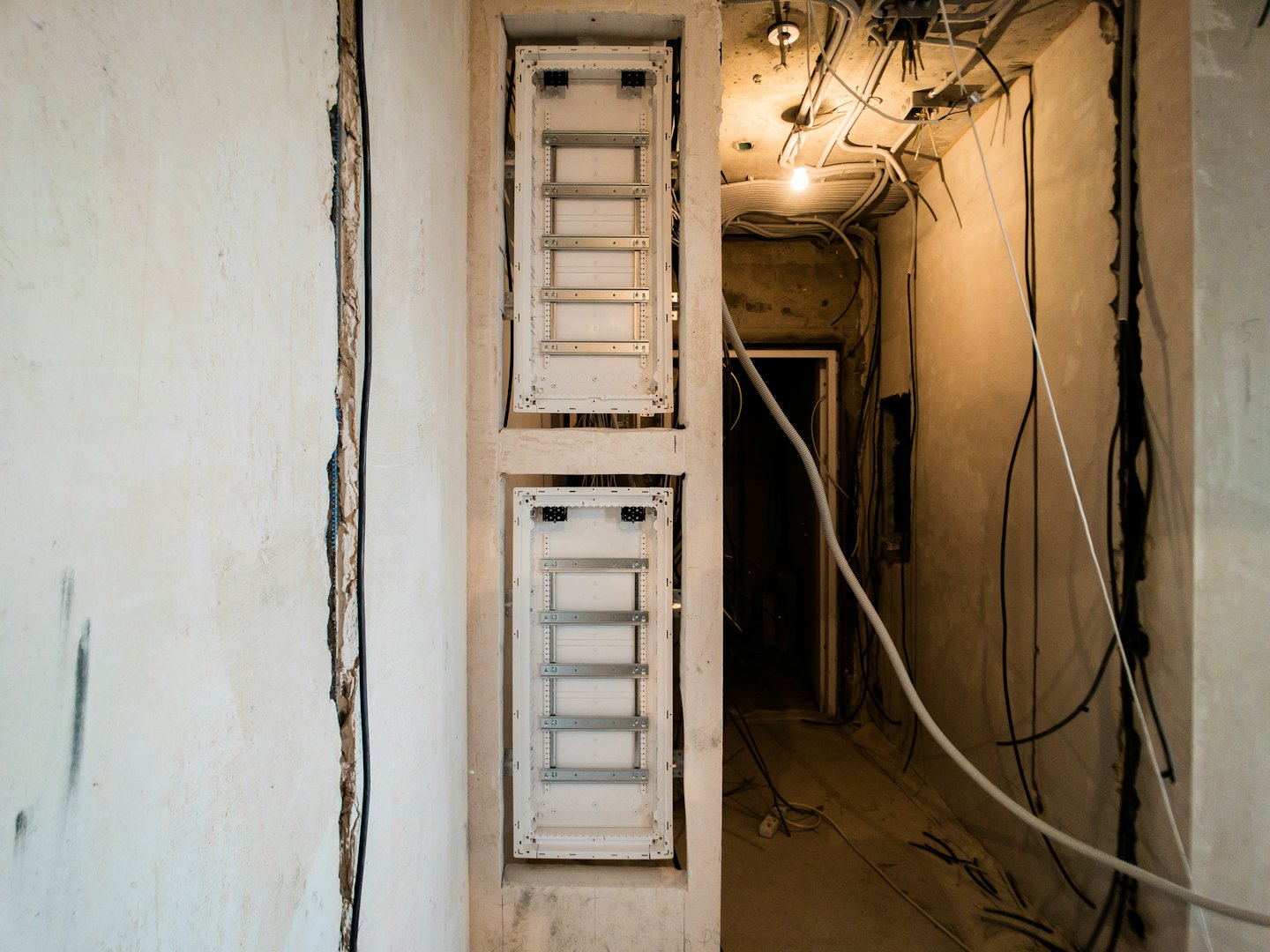 Two fuse boxes with tangled wires on unfinished concrete wall.